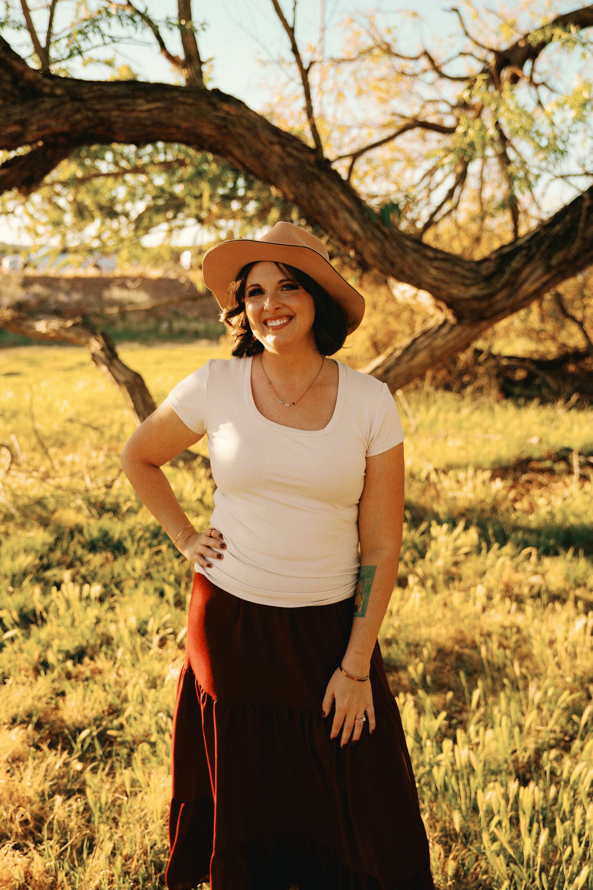 Shelbie Bouck, LCMHC, smiling beneath a tree in a sunlit field